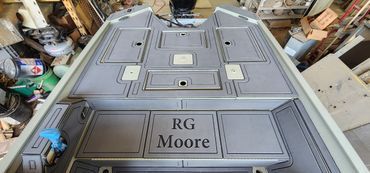 Gray metal door or panel with engraved “RG Moore” label, viewed from above in a workshop.