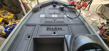 Black armored vehicle roof with hatches and a SEAARK logo in a workshop