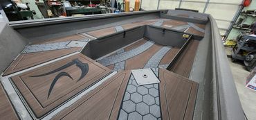 Boating deck with brown wood-look flooring, gray cushions, and angular seats in a workshop