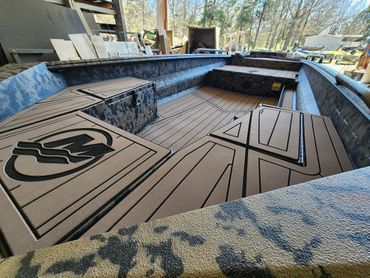 Custom in-ground empty pool with blue tiled edges and tan geometric floor panels in a backyard.