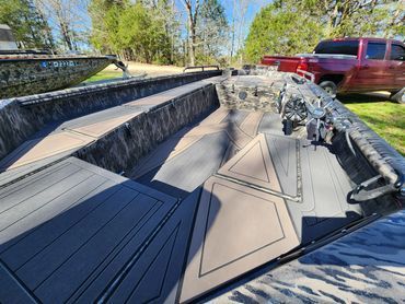 Folded black-and-tan boat interior laid out on a trailer in a driveway beside a red pickup truck.