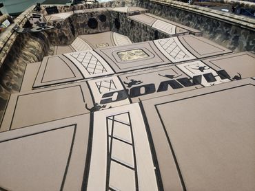 Stone amphitheater with a giant beige stage and dark painted lettering, seen from above