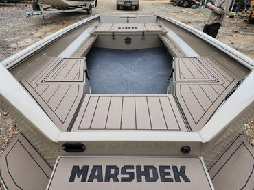 MARSHDEK-branded boat interior with tan deck panels and blue flooring at a boatyard