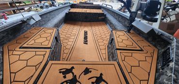 A narrow orange-and-black boat deck with geometric patterns and a central walkway in a dockyard.