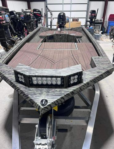 Custom boat hull on a workshop trailer, unfinished with gray deck and black trim.