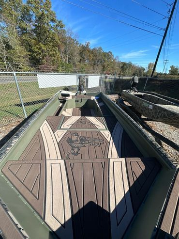 Empty trailer bed with brown and tan panels beside a chain-link fence on a sunny day