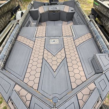 Empty gray and tan luxury boat deck viewed from above, with geometric flooring and rear seating area