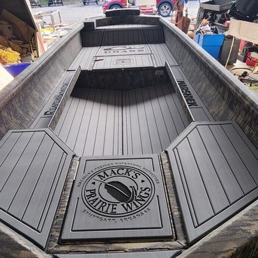 Custom black aluminum fishing boat deck with central storage compartment in a workshop setting