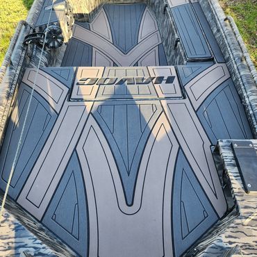 Top-down view of a dark gray armored vehicle roof with geometric panels and hatches, parked on a road.