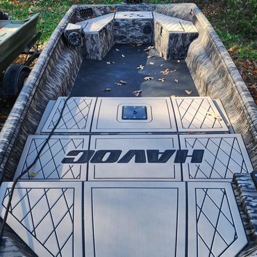 Camouflaged aluminum fishing boat interior with gray deck and black accents, seen from the stern.