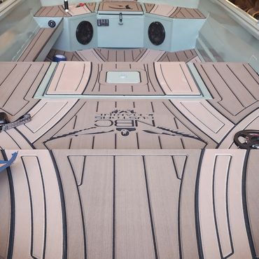 Boat deck with light wood flooring, blue upholstery, and built-in speakers and hatches.