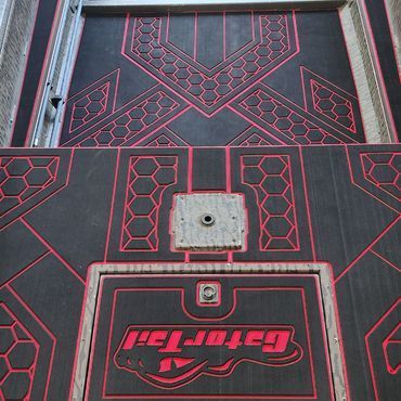 Red-and-black geometric metal gate with a sign and lock plate in the center