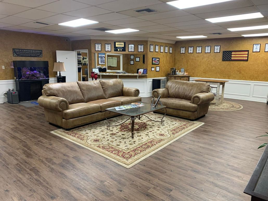 Waiting room with tan couches, glass coffee table, and patterned rug in a wood-paneled office lobby.