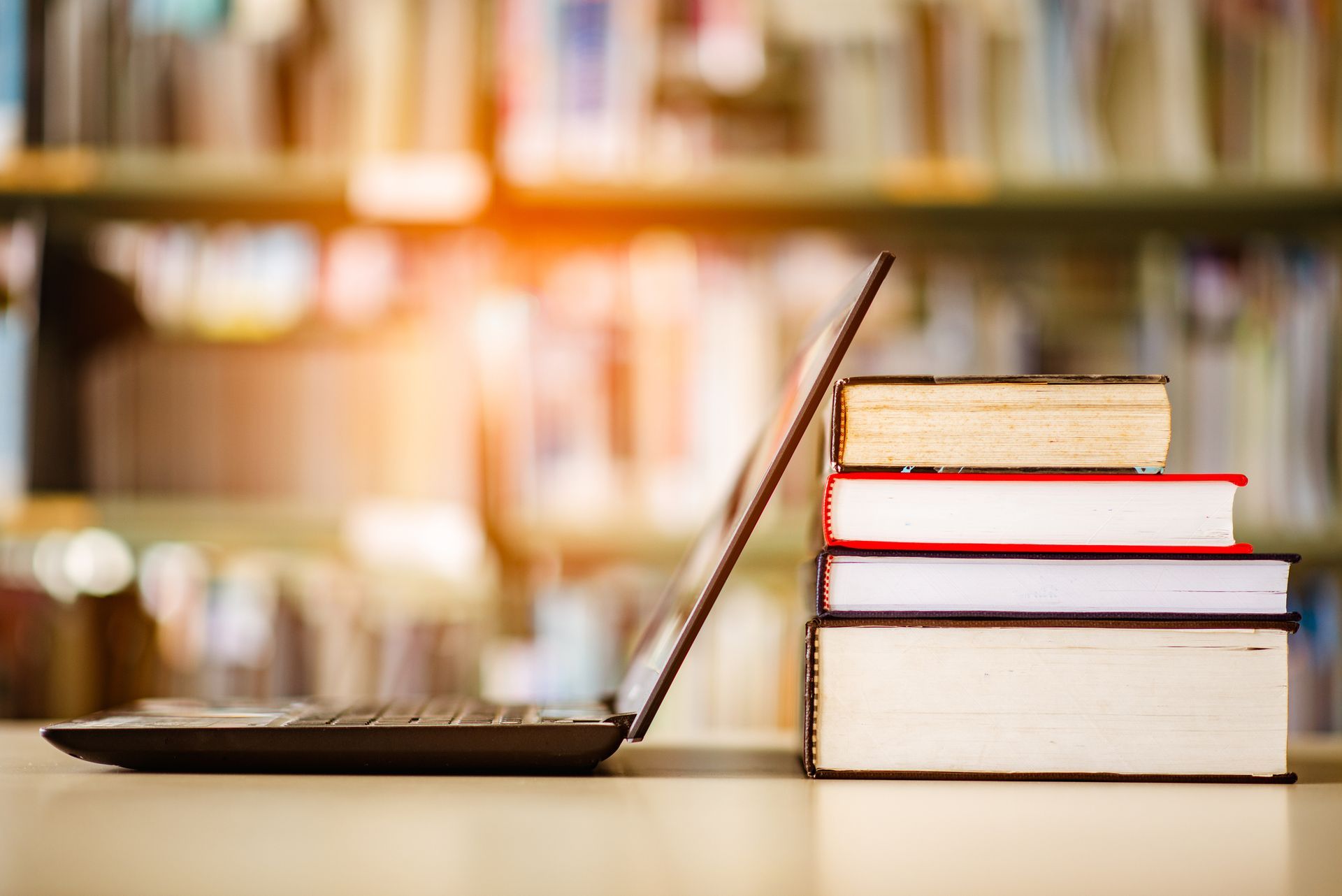 a stack of books with a laptop sitting on a table