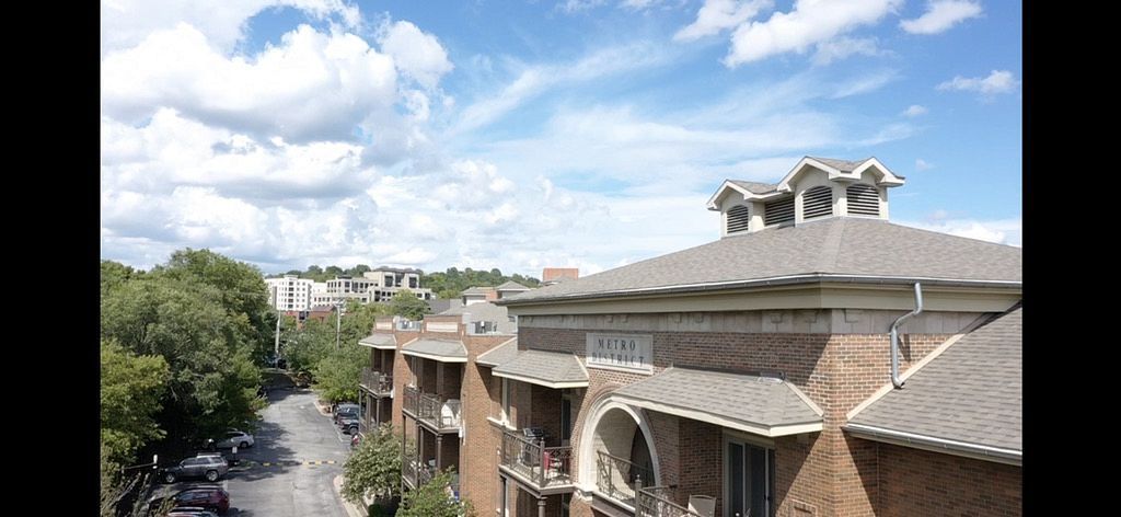An aerial view of a brick apartment building with a roof that is covered in shingles.
