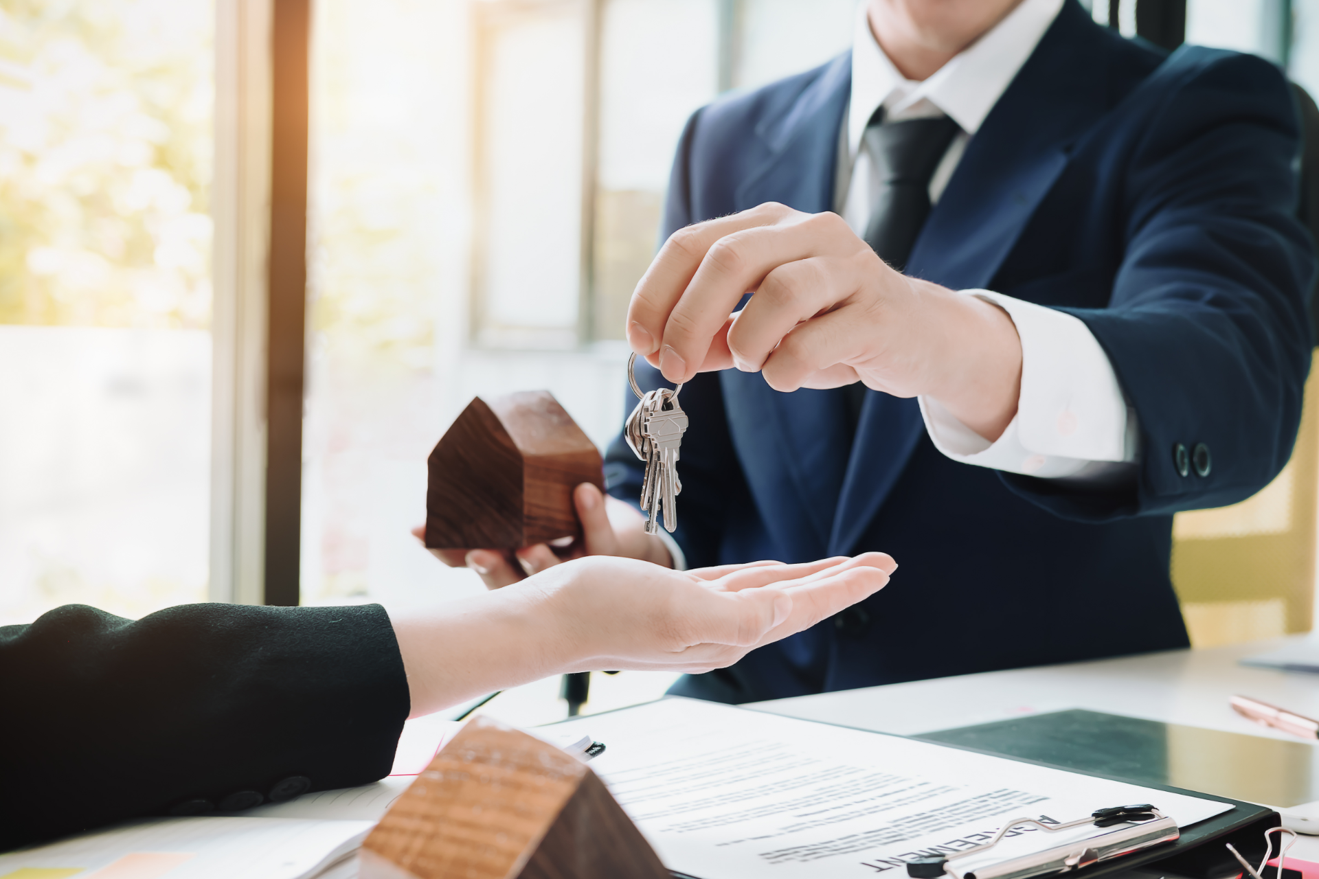 Businessperson handing over house keys during a property sale meeting