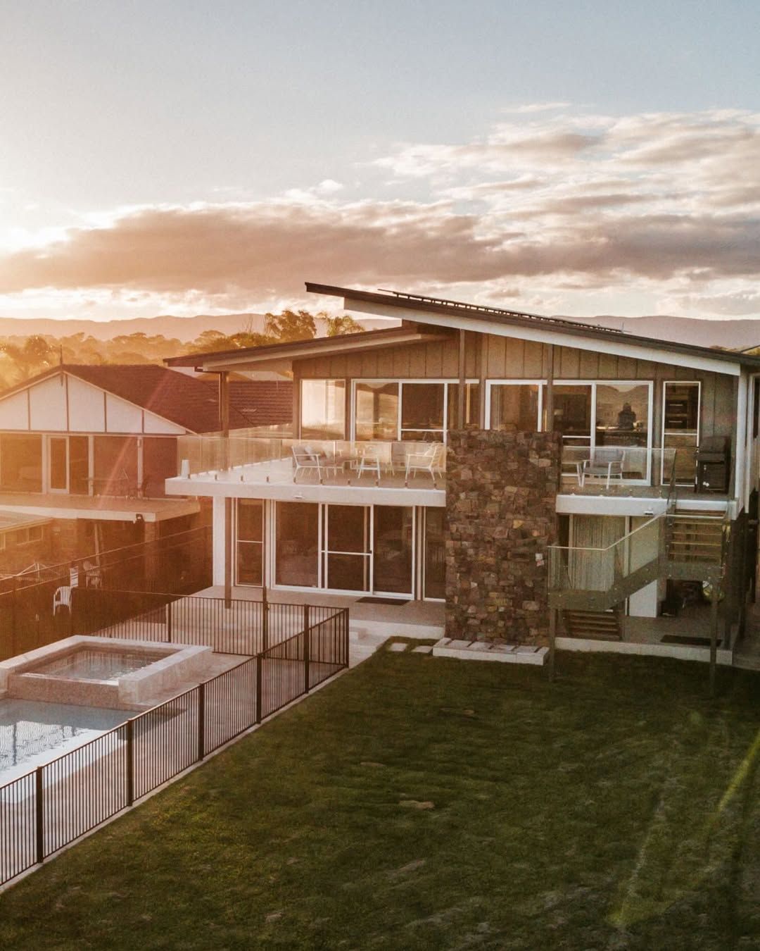 Modern House with Stone Facade and Slanted Roof at Sunset — QBC Constructions In Gerringong, NSW