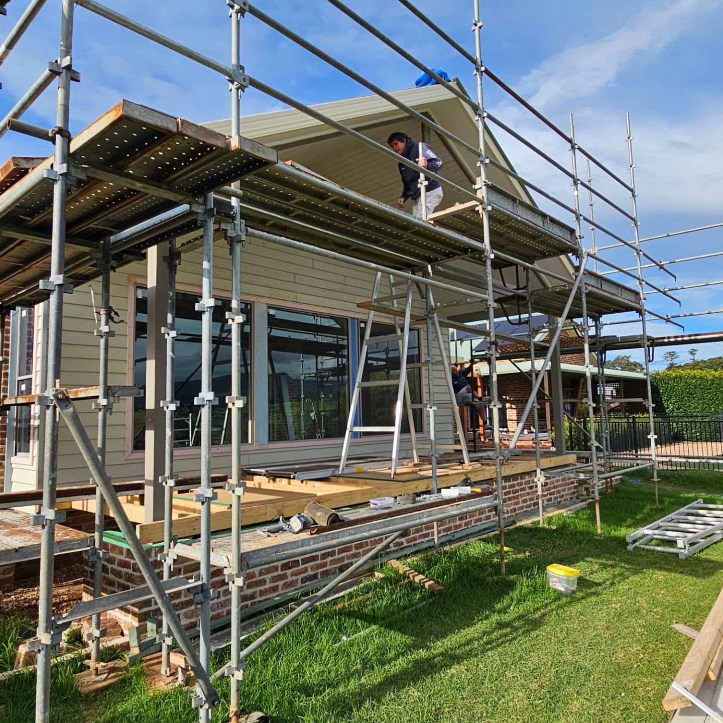 House Under Construction with Scaffolding and A Worker on The Roof — QBC Constructions In Kiama, NSW