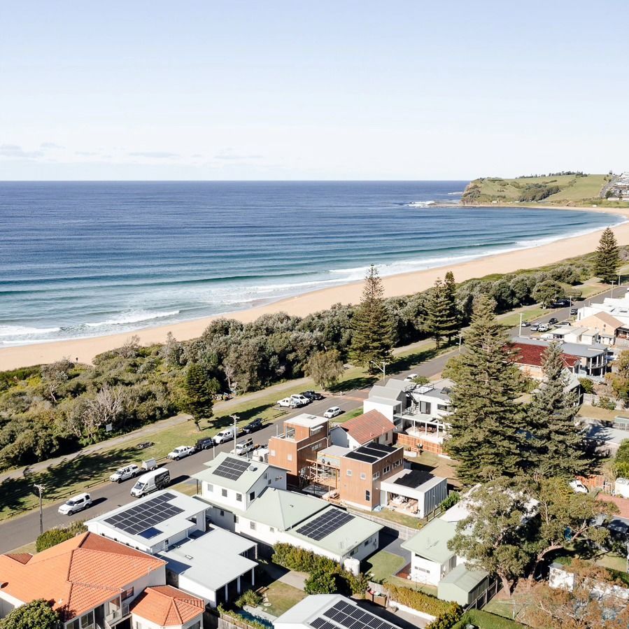 Coastal Town with Colorful Houses, a Sandy Beach, and Ocean Waves — QBC Constructions In Kiama, NSW