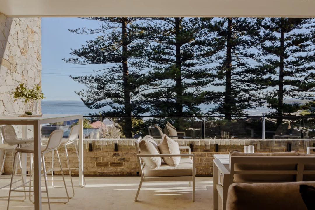 Balcony Seating Area Overlooking the Ocean with White Chairs — QBC Constructions In Kiama, NSW