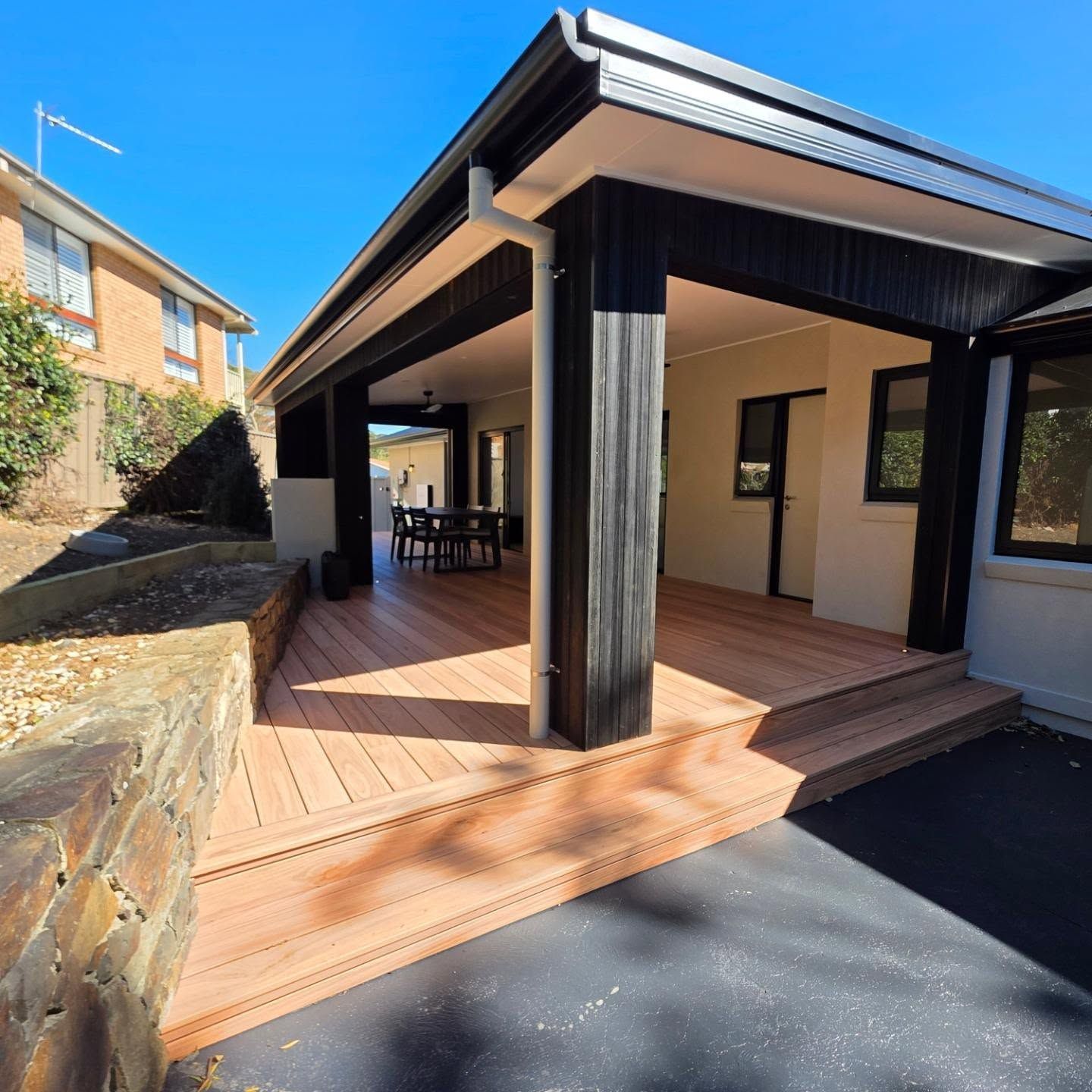 Covered Wooden Deck Patio Beside a House with Black Columns — QBC Constructions In Kiama, NSW