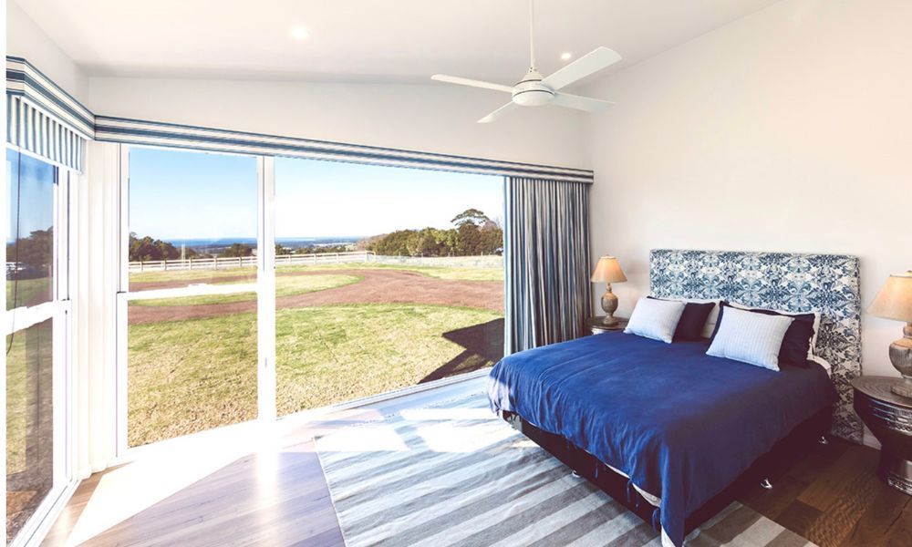 A Bedroom With a Large Bed and a Ceiling Fan — QBC Constructions In Willow Vale, NSW