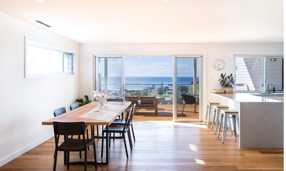 A Dining Room With a Table and Chairs and a View of the Ocean — QBC Constructions In Gerringong, NSW