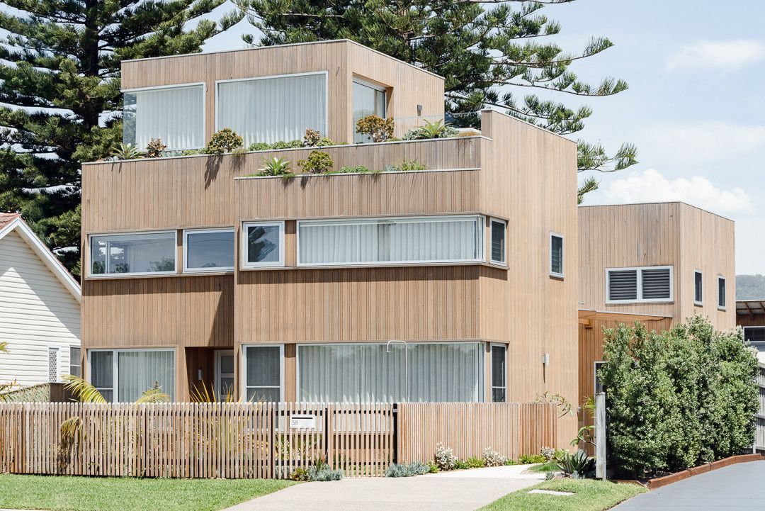Modern Two-story House With Orange And White Facade, Large Windows, And A Mountain Landscape Backdrop — QBC Constructions In Pacific 5, NSW