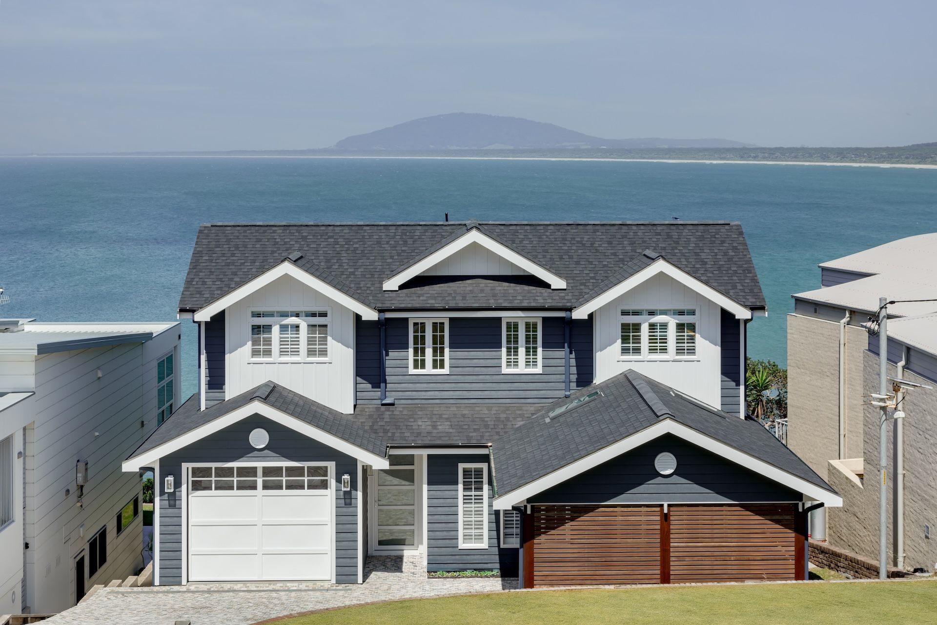 Gray Beach House Overlooking The Ocean With Distant Island And Blue Sky  — QBC Constructions In The Gables, NSW
