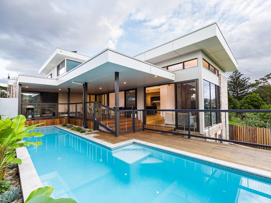 A Large Modern House With A Lot Of Windows And A Pool — QBC Constructions In Werri Beach, NSW