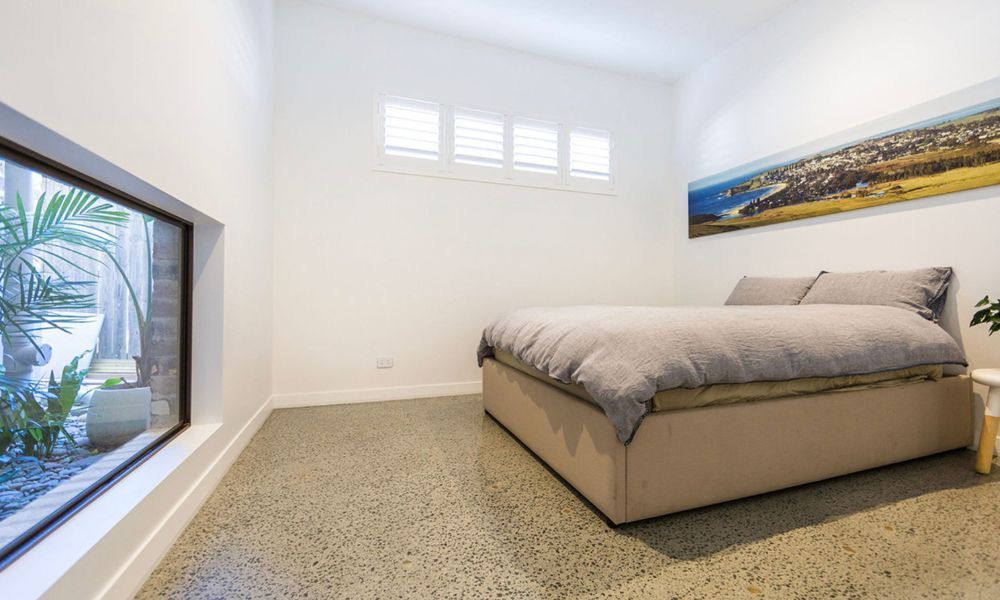 A Bedroom With a Bed and a Window With a Picture on the Wall — QBC Constructions In South Coast, NSW