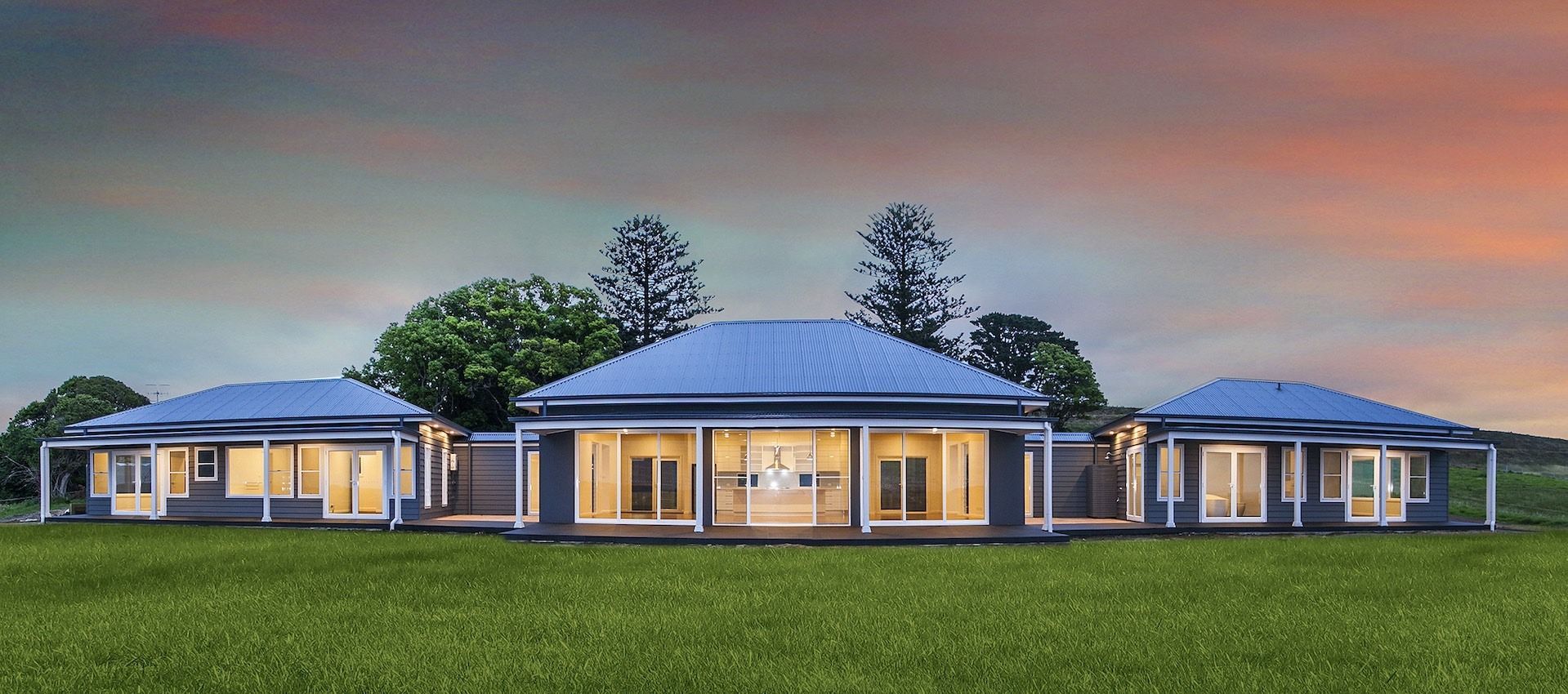 A Large House With a Blue Roof is Sitting on Top of a Lush Green — QBC Constructions In Kogarah, NSW