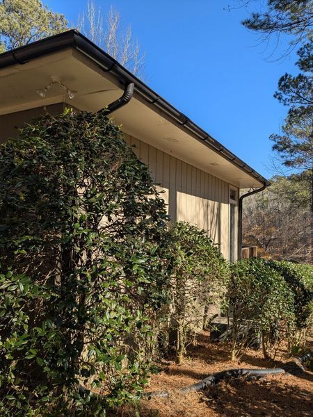 A house with a gutter on the side of it surrounded by trees.