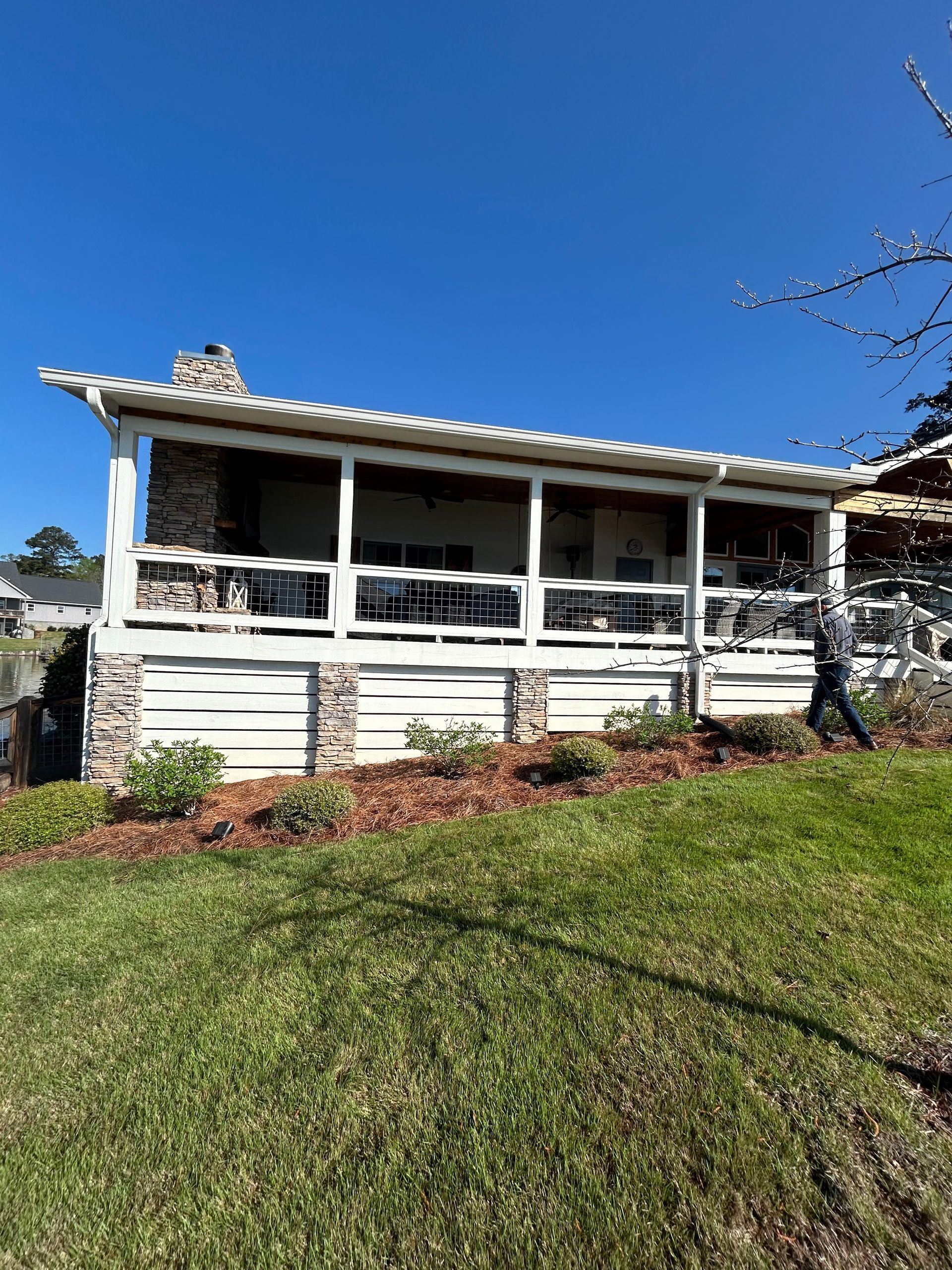 A white house with a large porch and a blue sky in the background.