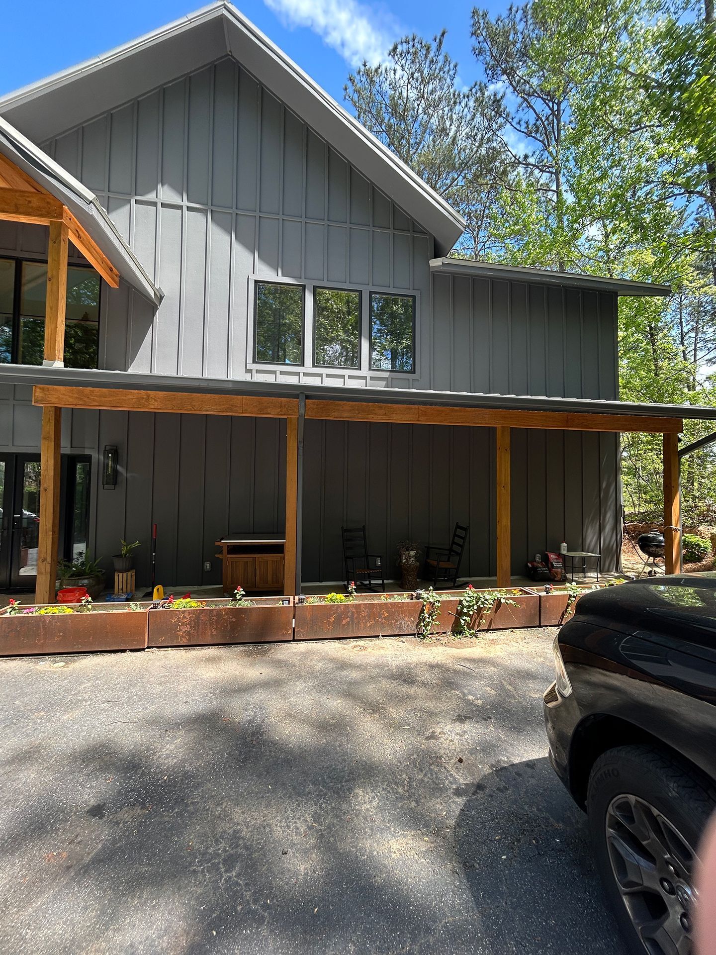 Gray two-story house with a covered porch, potted plants, and a black truck in the driveway