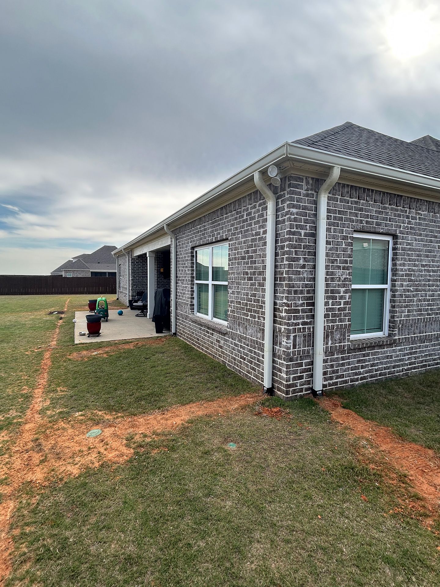 Brick house exterior with white trim and a small lawn under a cloudy sky