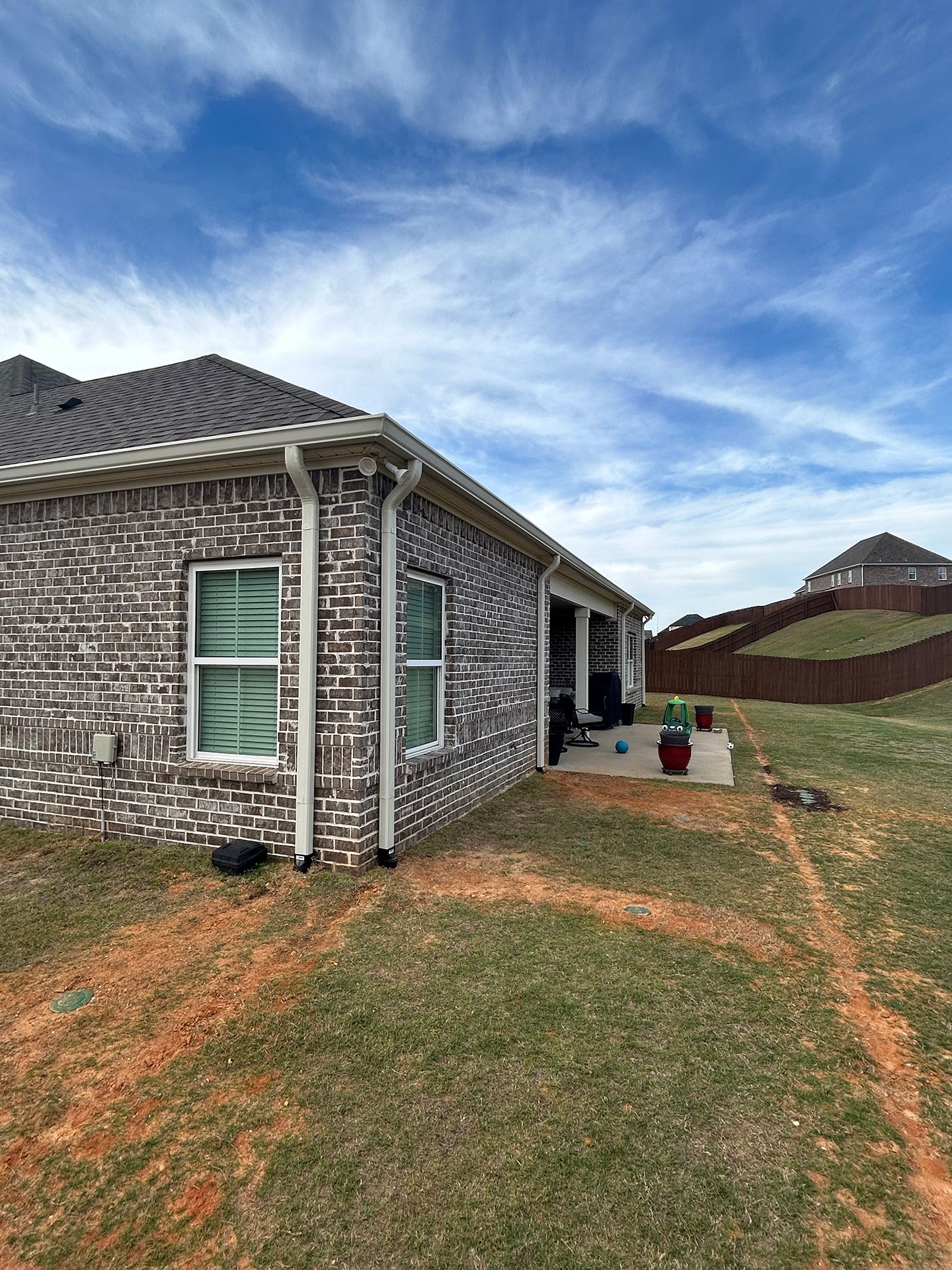 Brick house exterior with white trim, grassy yard, and cloudy blue sky