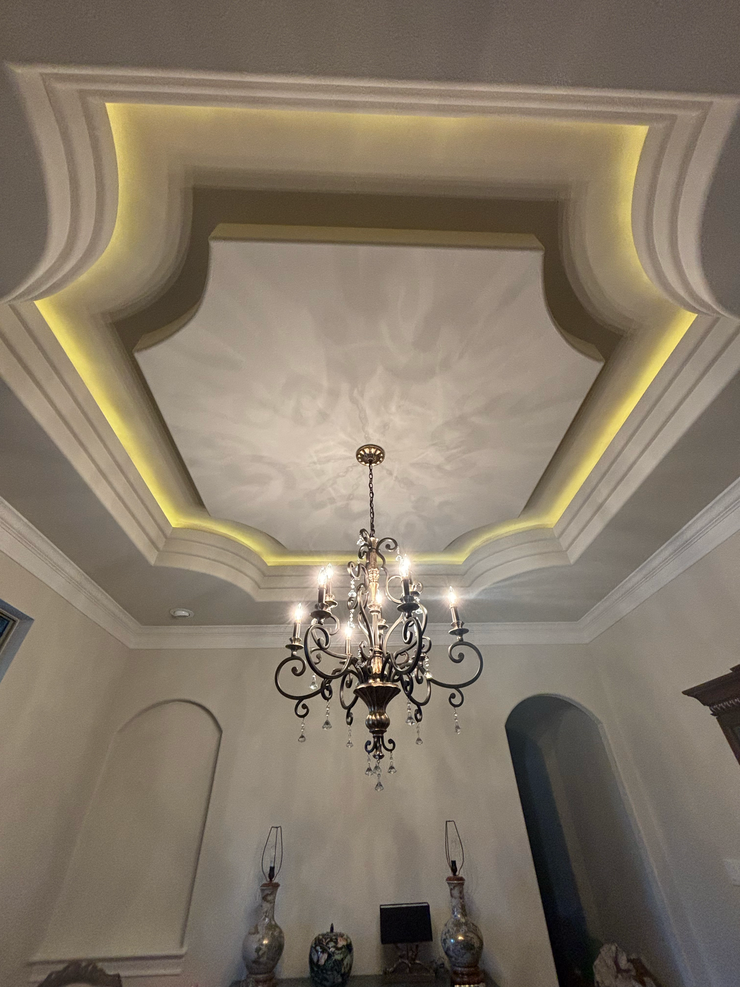 Person installing a track lighting fixture on a textured off-white ceiling; hands adjusting the light head.