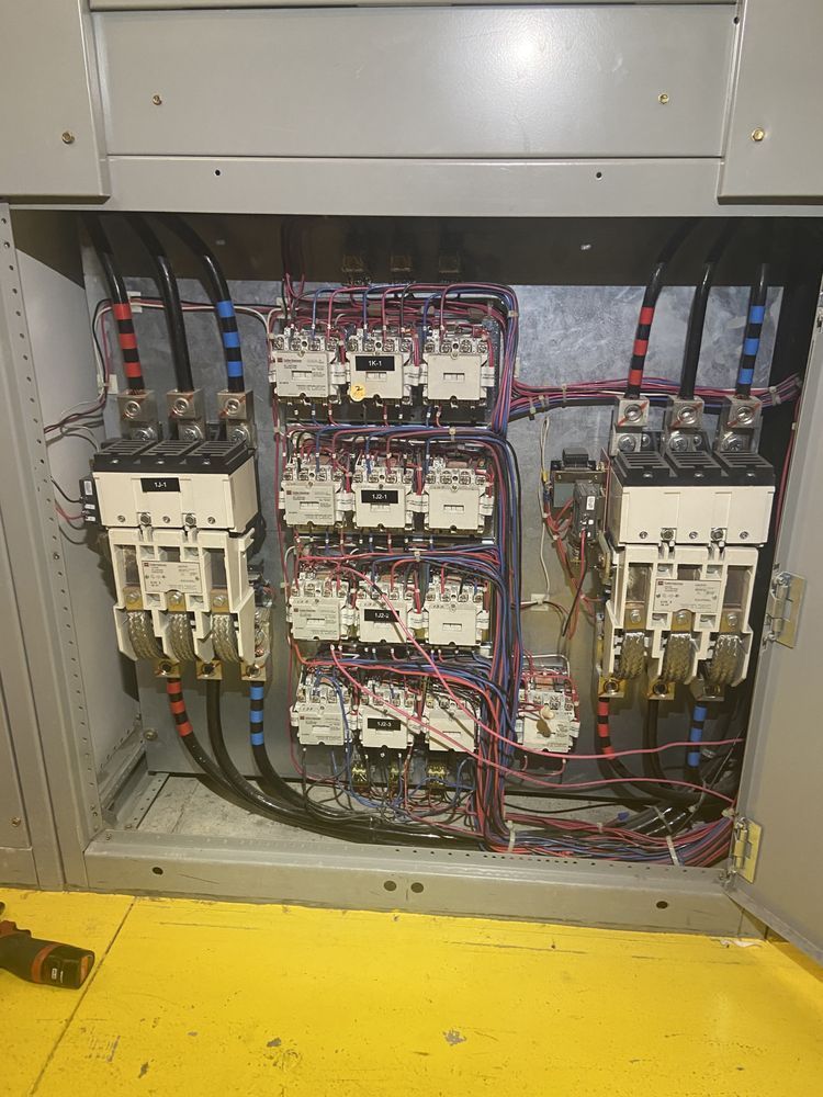 Electrical control panel with multiple circuit breakers and wiring inside a metal cabinet.