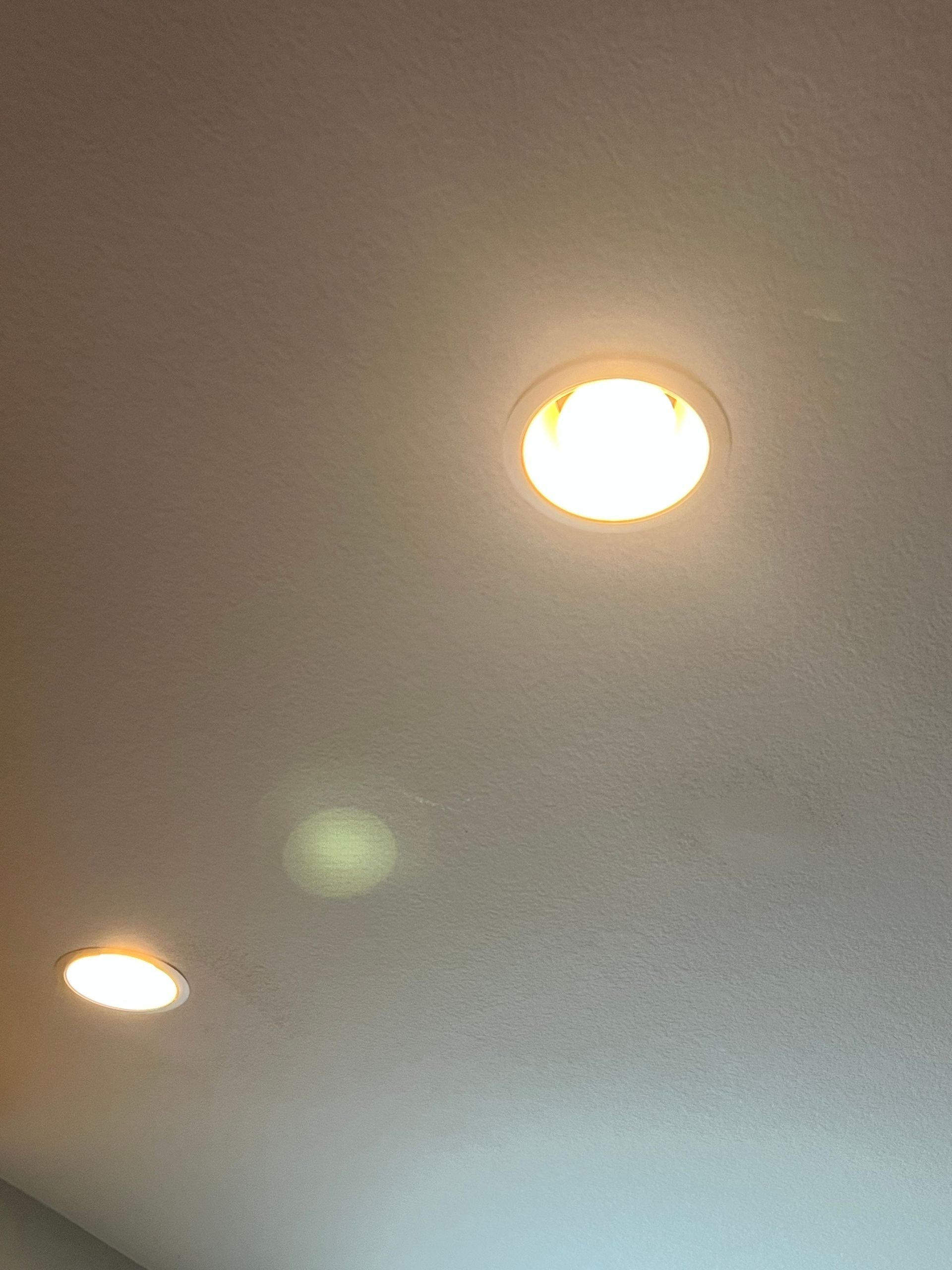 Three recessed ceiling lights illuminate a white ceiling.