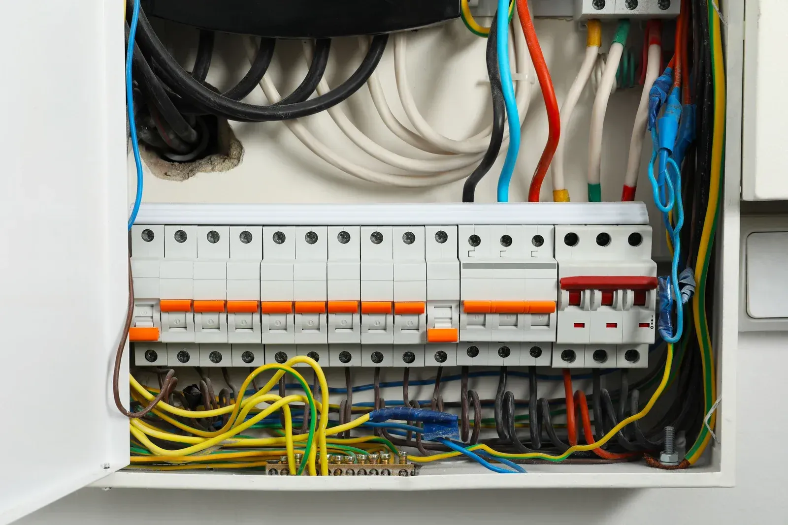 Open electrical panel with colored wires connected to circuit breakers.