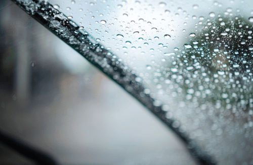 Raindrops on a car windshield with blurred street lights in the background