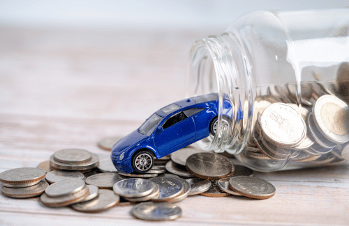 Blue toy car tipped out of a glass jar onto scattered coins