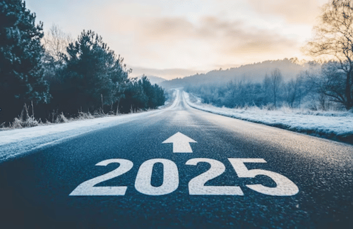 Snowy road stretching into the distance with “2025” painted on the pavement and an arrow ahead