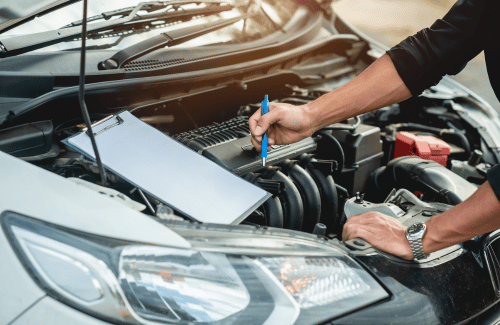 Mechanic checking engine with a blue pen under an open car hood