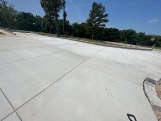 Empty concrete parking lot beside trees on a sunny day