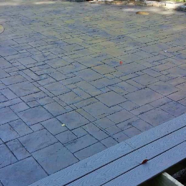 A brick walkway with a wooden deck in the background.