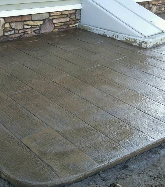 A concrete walkway with a stone wall in the background