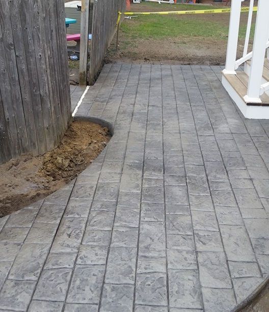 A brick walkway with a wooden fence in the background