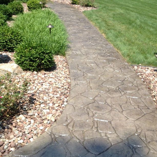 A stone walkway leading to a lush green lawn